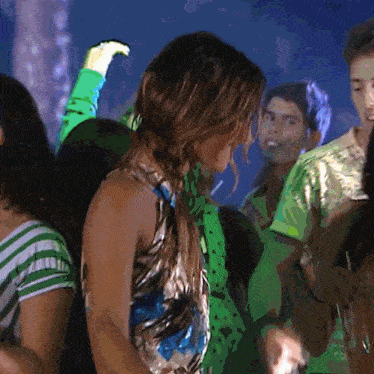 a woman in a green top stands in a crowd
