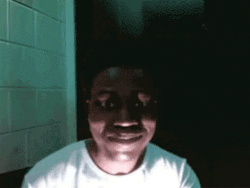 a man in a white shirt is smiling with his eyes closed