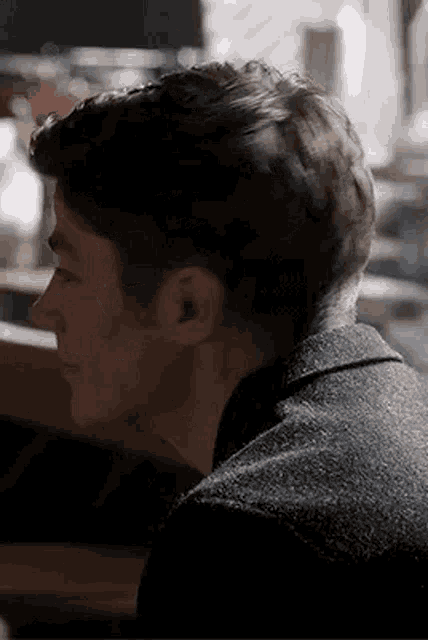 a close up of a man 's face and neck while sitting at a table in a dark room .
