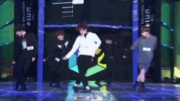 a group of young men are dancing on a stage in front of a sign that says " the unit "