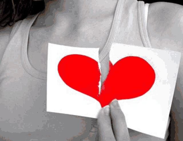 a woman is holding a piece of paper with a heart on it