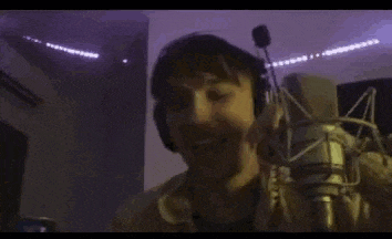 a man is drinking a soda from a can in front of a microphone .