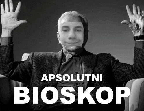 a black and white photo of a man with his hands in the air and the words apsolutni bioskop behind him