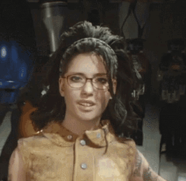 a close up of a woman wearing glasses and a tan vest