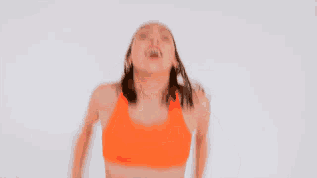 a woman in an orange sports bra is dancing