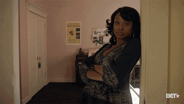 a woman with her arms crossed is standing in a room with a bet logo on the bottom