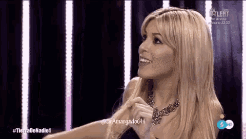 a woman in a necklace is smiling in front of a screen that says tierra de nadie