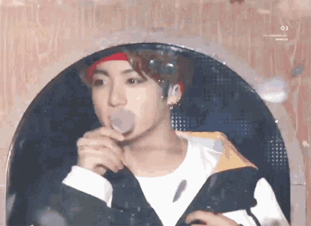 a young man is blowing bubbles out of his mouth while wearing a red headband .