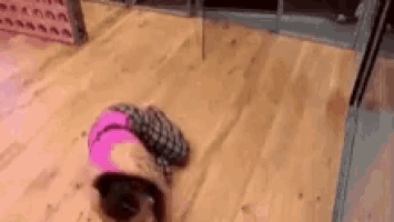 a woman in a pink top is laying on her back on a wooden floor .