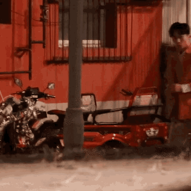 a man standing next to a red motorcycle and a red vehicle