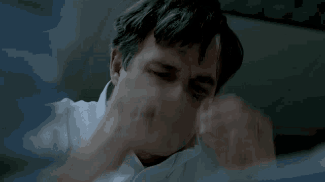 a close up of a man 's face with his eyes closed and his hand on his face .