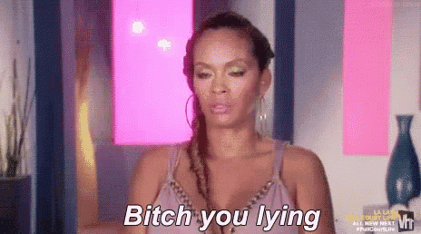 a woman in a purple top is standing in front of a pink wall and says `` bitch you lying '' .