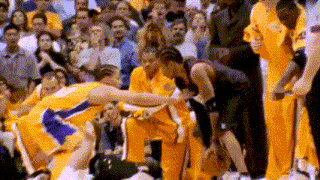 a basketball player is being helped off the court by a teammate while a crowd watches .