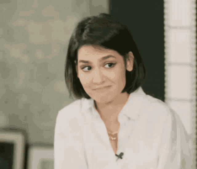 a woman wearing a white shirt with a microphone on her neck