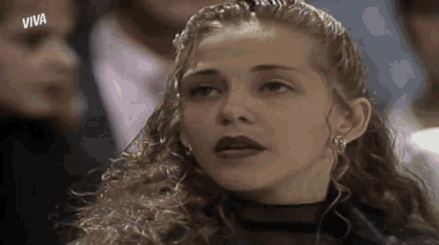 a woman with curly hair is sitting in a crowd with the word viva on the bottom