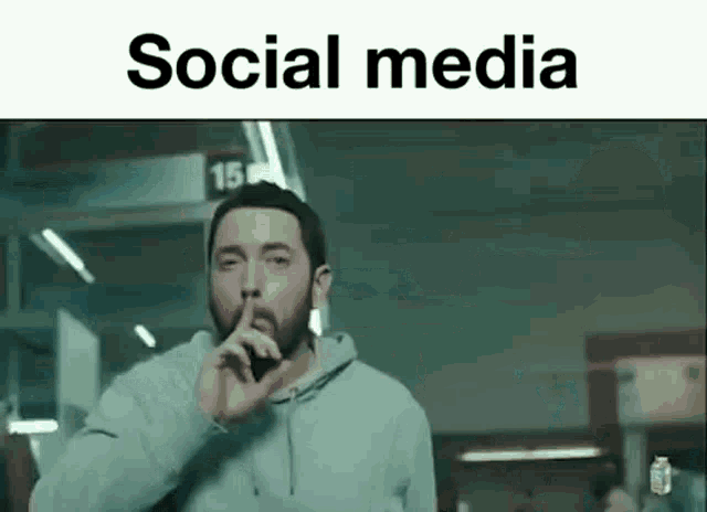 a man with a beard is making a silence sign with his finger .