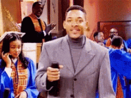 a man in a suit is holding a cell phone in front of a group of people
