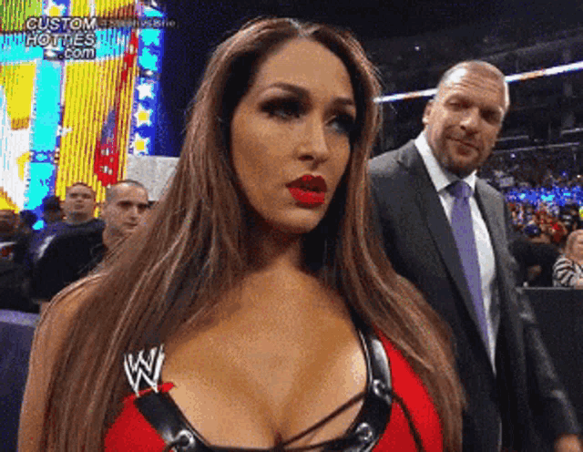 a woman in a red top with the letter w on it stands in front of a man in a suit
