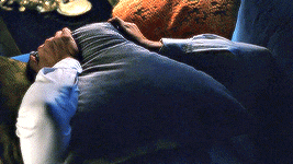 a man with a beard laying on a blue couch