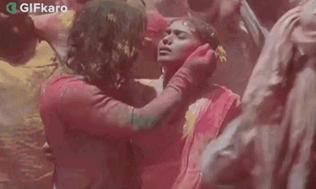 a man is touching a woman 's breast while a group of people are playing holi .