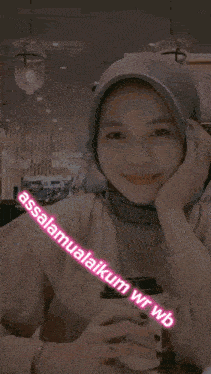 a woman wearing a hijab is smiling and holding a cup of coffee with the words assalamualaikum wr wb written on it