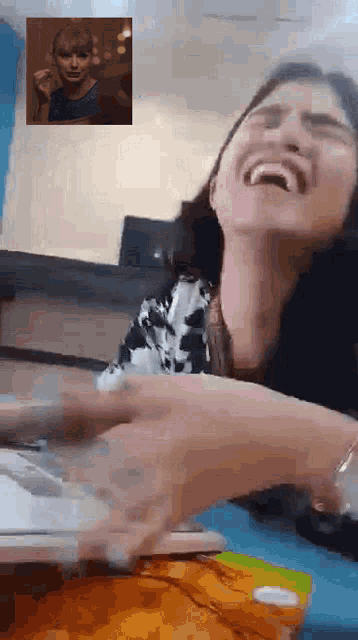 a woman is laughing while talking on a video call