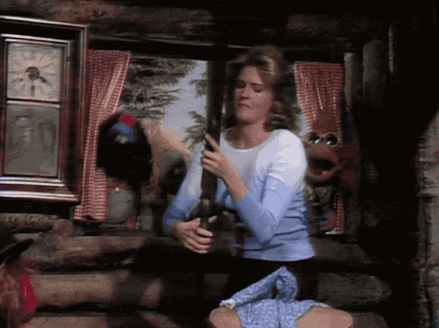 a woman in a blue sweater is holding a puppet in front of a window