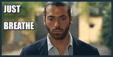 a man with a beard is wearing a suit and has the words just breathe above him