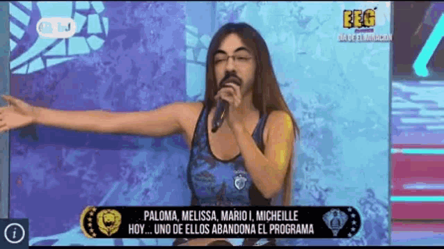 a woman with a beard is singing into a microphone on a tv show .