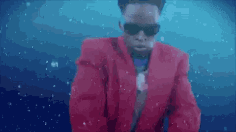 a man wearing sunglasses and a red jacket is swimming in the water .