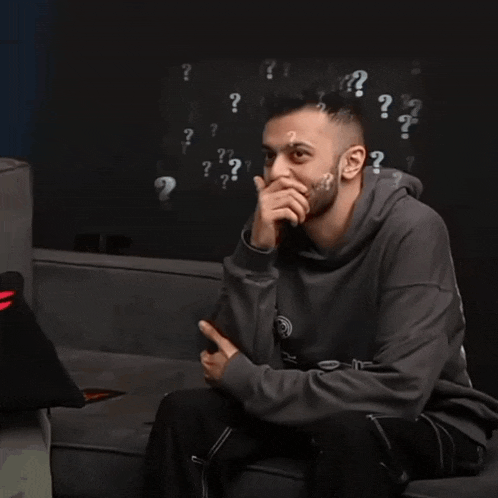 a man with a beard is sitting on a couch with a question mark above his head