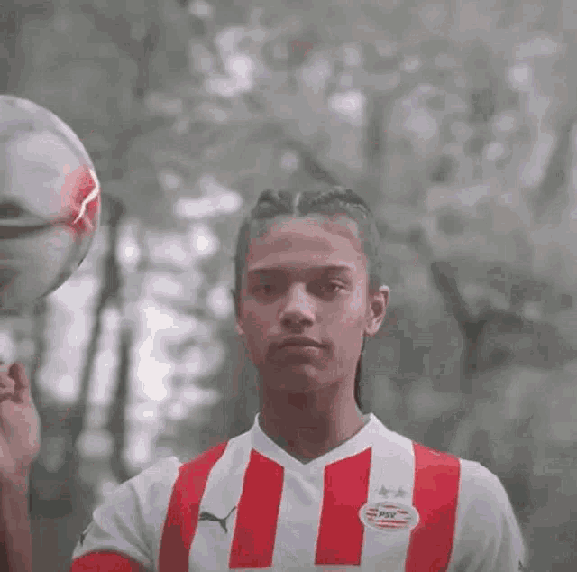 a man in a red and white striped shirt is holding a soccer ball with a lightning bolt on it