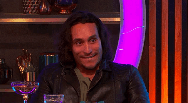 a man with a surprised look on his face is sitting at a table with a glass of water