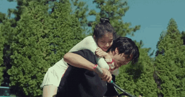 a man is carrying a woman on his back while playing tennis .