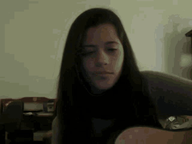 a woman with long dark hair is playing a guitar