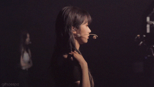 a woman with a microphone in her mouth is standing in the dark