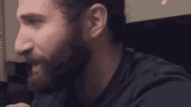 a man with a beard is looking at the camera with a serious look on his face