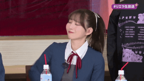 a girl with a ponytail is drinking from a bottle