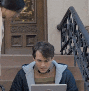 a man sits on a set of stairs using a laptop computer