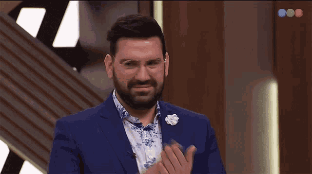 a man in a blue suit is applauding with a few emoji hands behind him