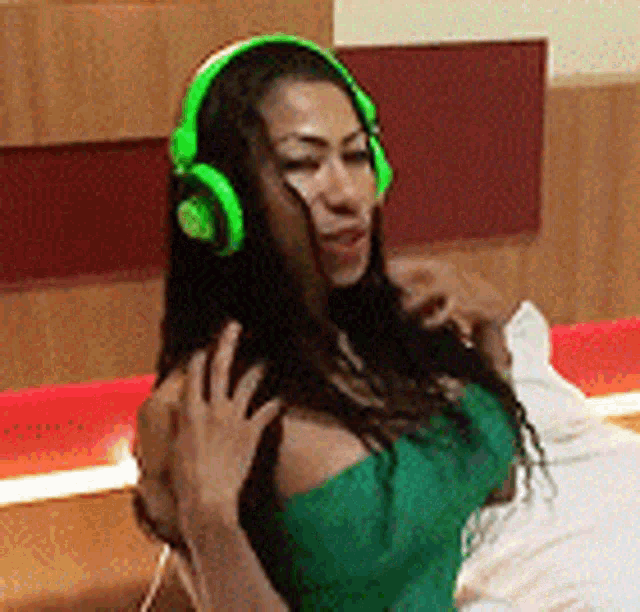 a woman in a green dress is wearing green headphones