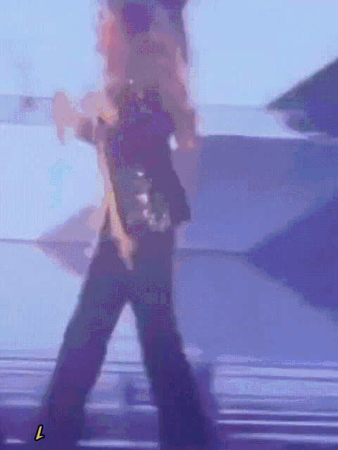 a person is dancing on a stage and the letter l is visible in the corner