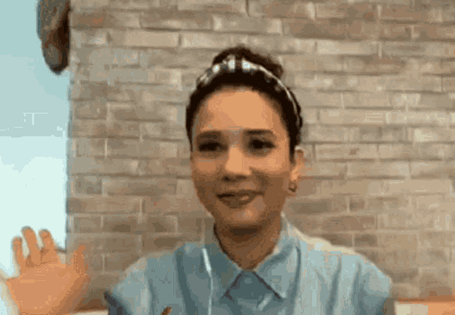 a woman wearing headphones is sitting in front of a brick wall and smiling .