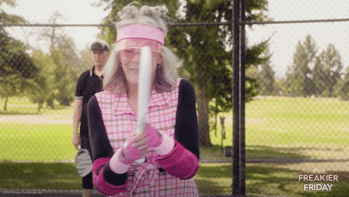 a woman is holding a baseball bat in front of a fence with freakier friday written on it