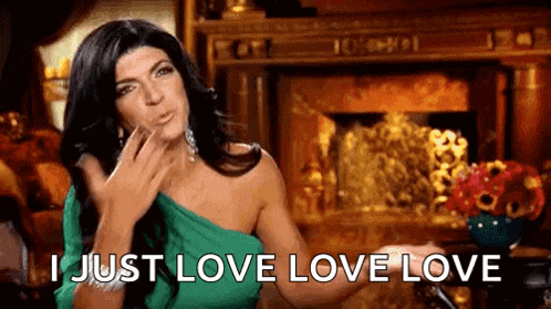 a woman in a green dress is blowing a kiss while sitting in front of a fireplace .