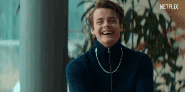 a man wearing a blue sweater is laughing with a netflix logo in the corner