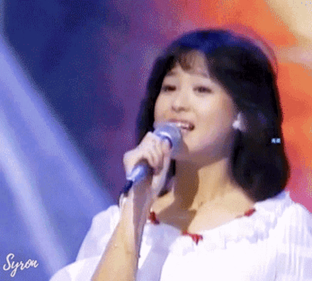 a woman singing into a microphone with the name syron written on the bottom