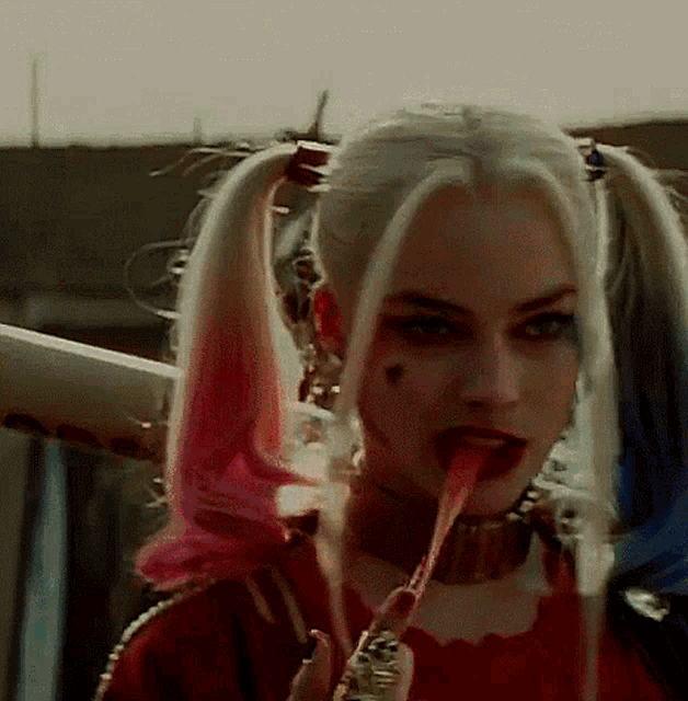 a woman in a harley quinn costume is eating a lollipop .