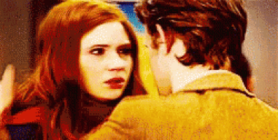 a man and a woman are looking at each other . the woman has red hair and the man is wearing a yellow jacket .