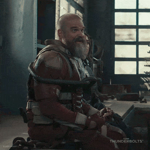 a man with a beard is laughing while sitting in a wheelchair
